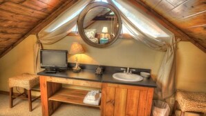 A small, cozy bathroom with a wooden vanity, a mirror, a sink, and a television.