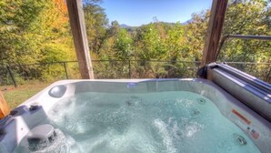 A hot tub with a view of autumn trees and mountains.