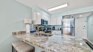 A modern kitchen with a granite countertop, stainless steel appliances, and a built-in microwave.
