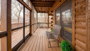A wooden deck with a covered porch, a chair, and a small plant.