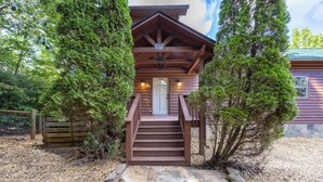 A wooden cabin with a front door, a staircase, and a porch.