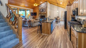 A spacious kitchen with wooden cabinets, a stone fireplace, and a large island.