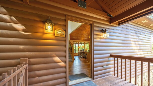 A wooden cabin with a wooden staircase leading to a deck.