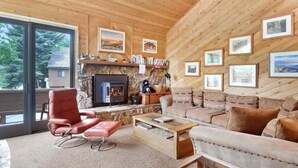 A cozy living room with a fireplace, wooden walls, and framed pictures. - Snowflower 53: Spacious, Partial Mountain Views (Mammoth Lakes)