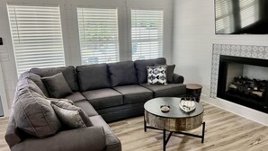 En moderne stue med en modulsofa, et rundt sofabord og en pejs.