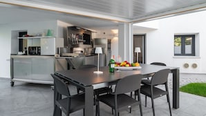 A modern kitchen with a dining area, featuring a large table with chairs, a refrigerator, and a sink. - WLofts 12 by Klodge - cozy design holiday suite (Olbia)