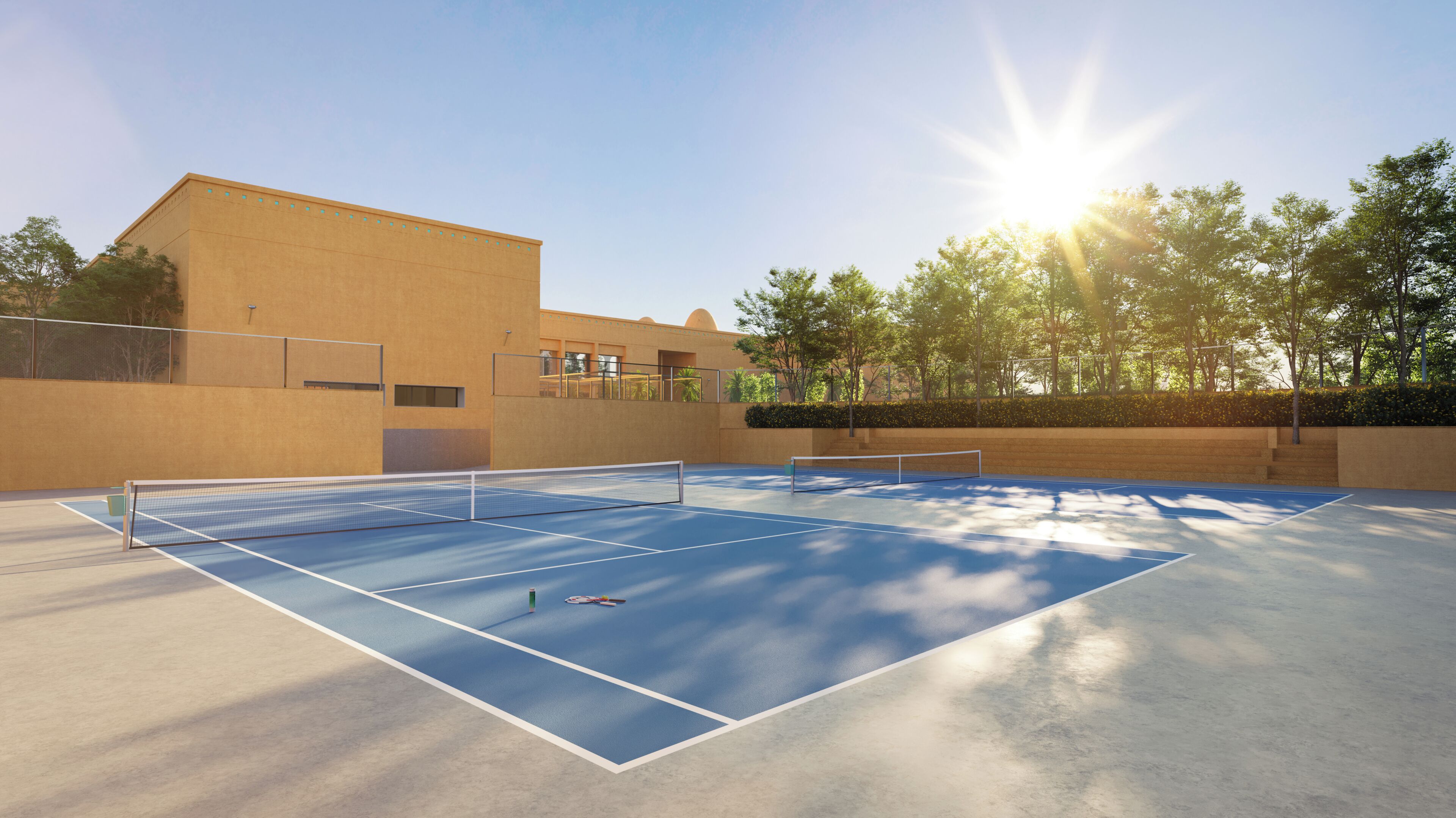 An outdoor tennis court with a net, surrounded by a low wall and trees.