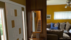 A living room with a brown sofa, a glass cabinet, and a white door. - Large, Beautiful Mid Century Mountain House..... (South Williamsport)