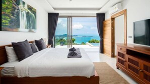 A bedroom with a bed, a flat-screen TV, a ceiling fan, and a large window with a view of the ocean. - `Villa Majesta`Amazing View, luxury 4br Pool villa (Koh Samui)