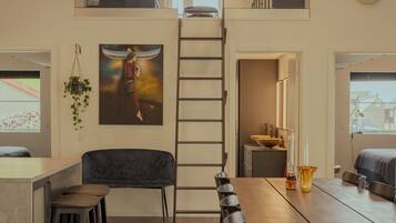 Eine moderne Loft-Küche mit einem langen Esstisch, Barhocker und einer Treppe, die zu einer oberen Ebene führt.