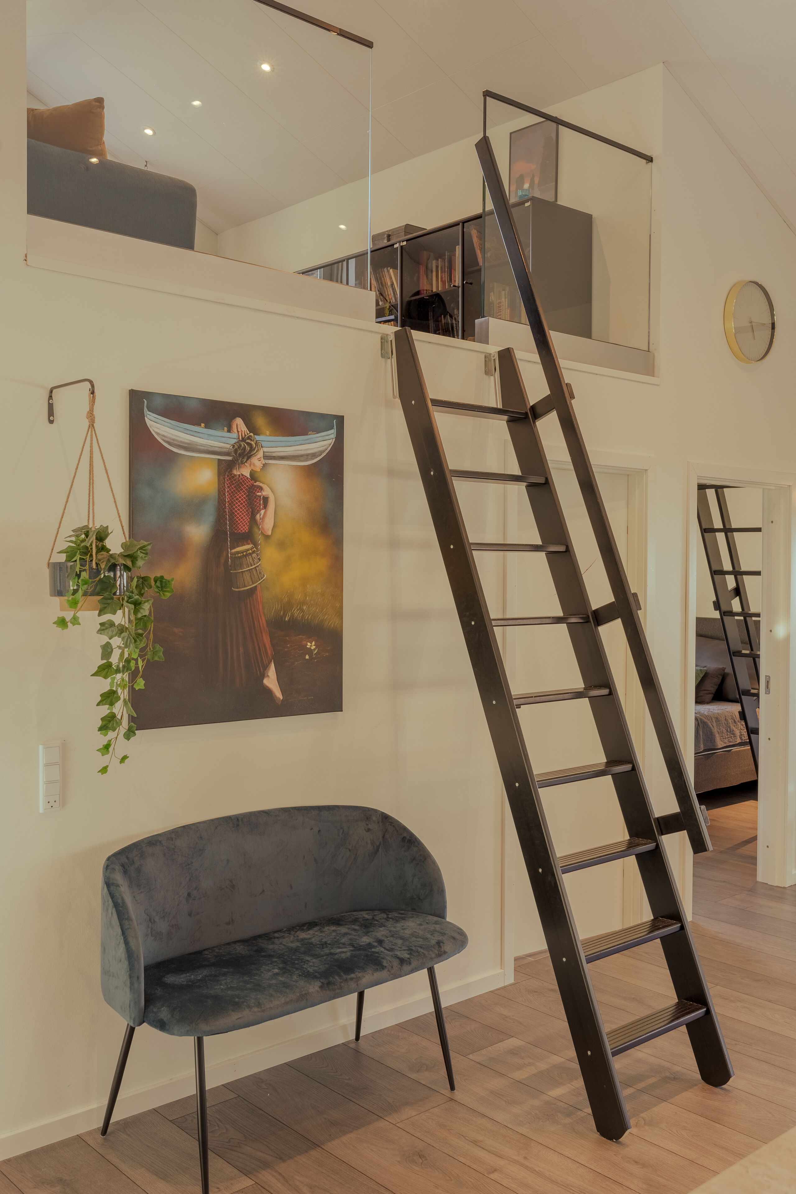 Ein modernes Interieur mit einem Raum im Loft-Stil, einem dunkelblauen Sofa, einer Wendeltreppe und einem großen Gemälde.