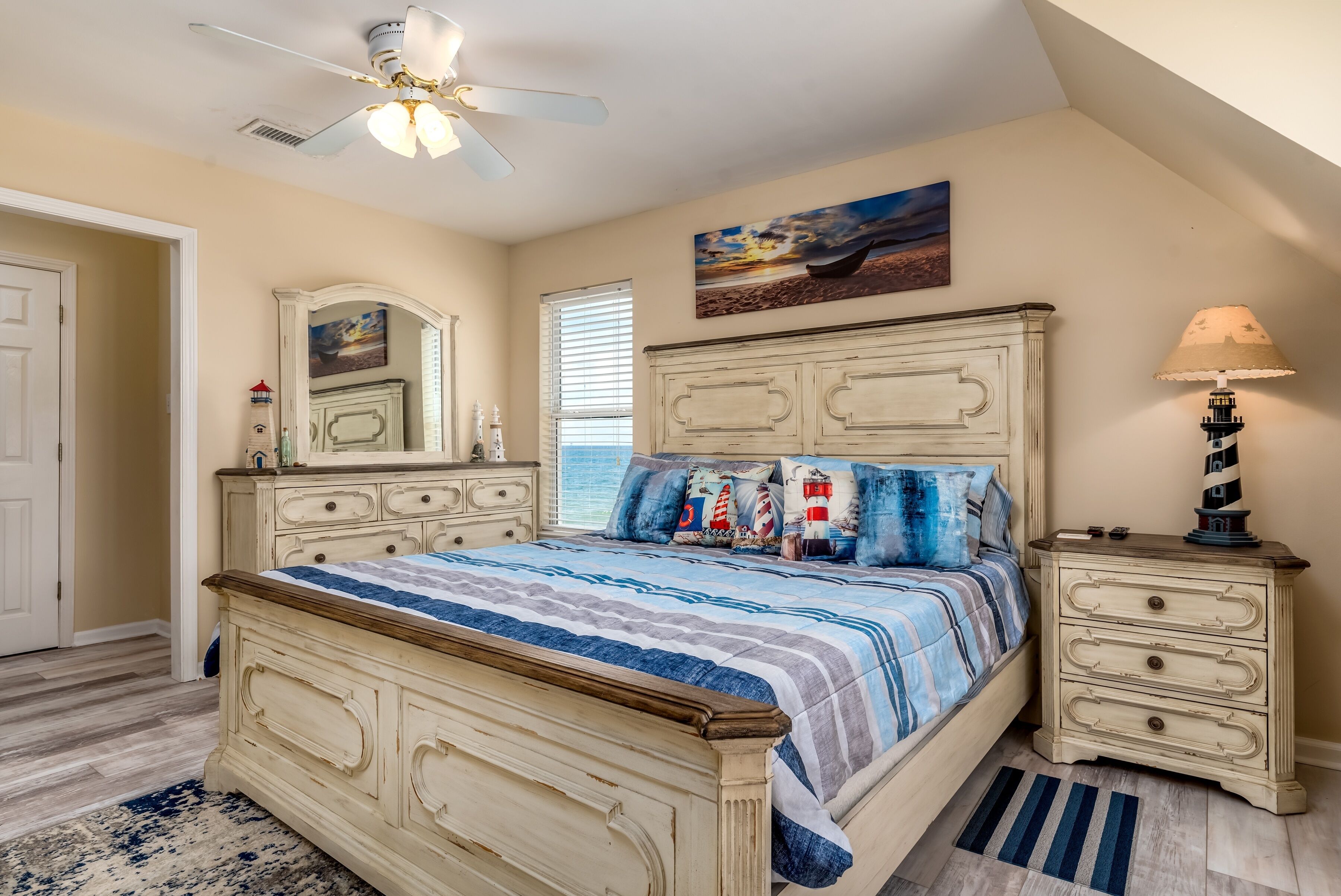 A bedroom with a bed, dresser, nightstand, and ceiling fan.
