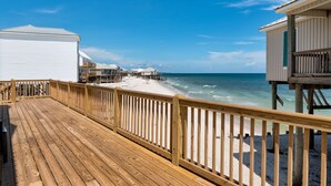 A wooden deck leading to beach cottages with ocean views. - The Boat House - 106 Westward Ho 4 Bedroom Home by RedAwning (Dauphin Island)