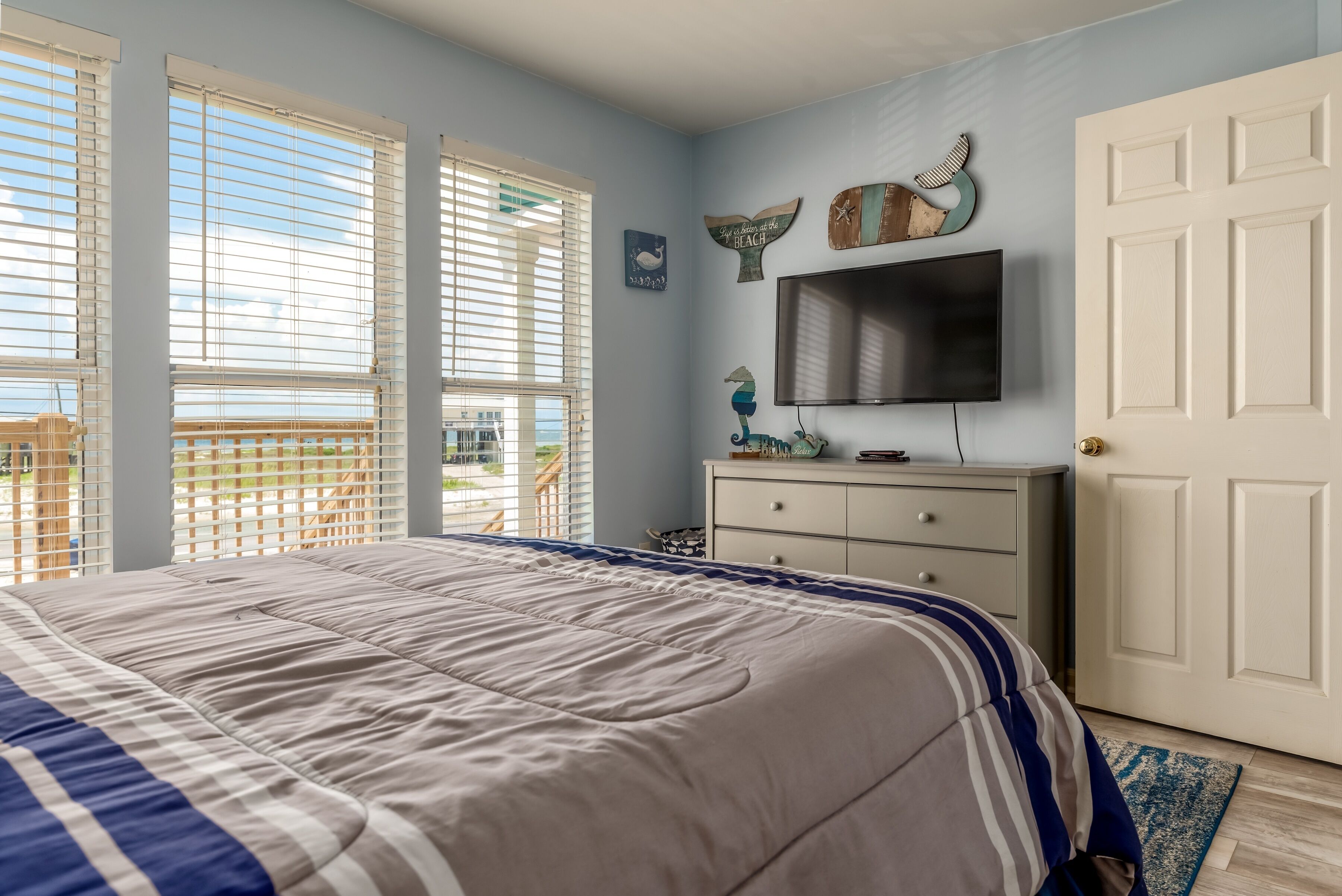 Un dormitorio con una cama grande, un aparador, un televisor y decoración en la pared.