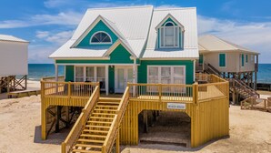 A beach house with a green and white exterior, two decks with wooden railings, and a sign reading "BEACH HOUSE". - The Boat House - 106 Westward Ho 4 Bedroom Home by RedAwning (Dauphin Island)