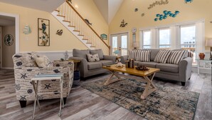 A spacious living room with a high ceiling, a staircase, and nautical-themed decor. - The Boat House - 106 Westward Ho 4 Bedroom Home by RedAwning (Dauphin Island)