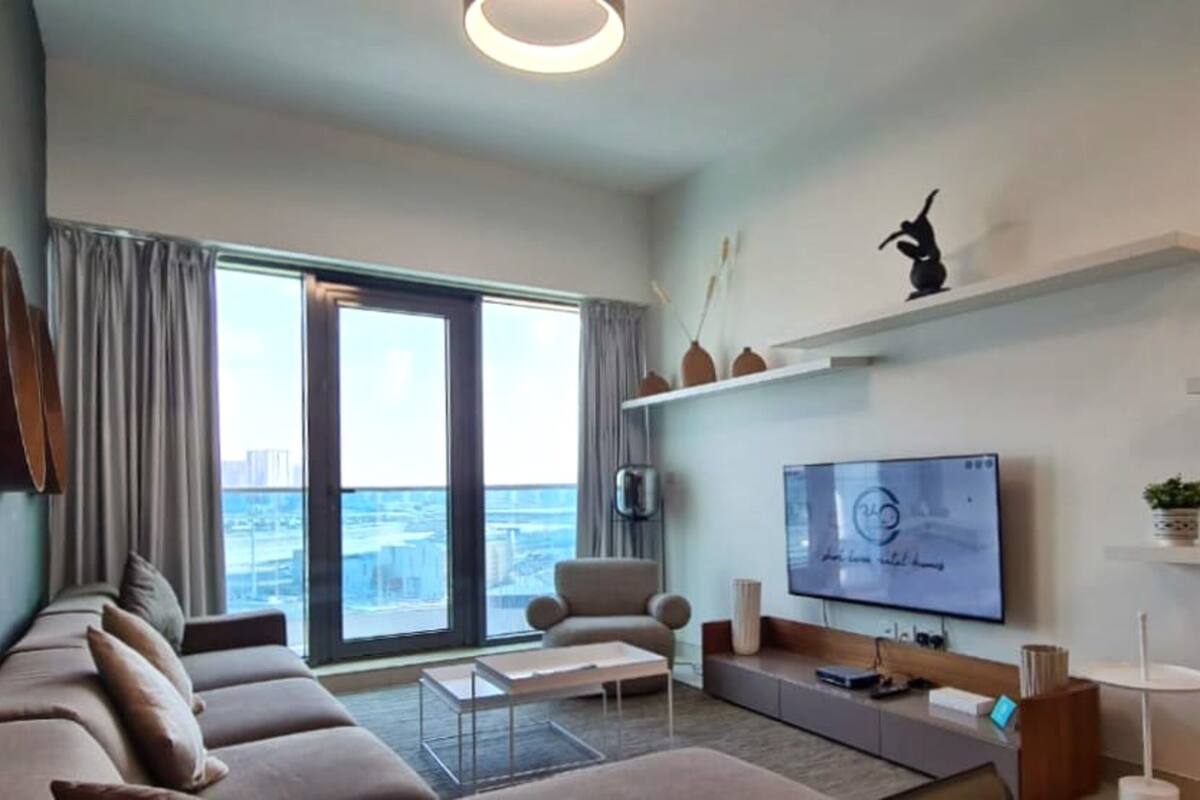 Una sala moderna con un sofá, una mesa de centro y un televisor de pantalla plana montado en la pared.