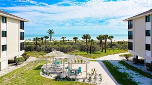 A resort with a beach view, outdoor seating area, and a covered pavilion.