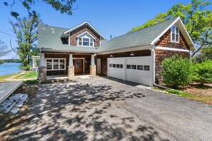 Une maison à deux étages avec un garage, une entrée en pierre et une vue sur un lac.