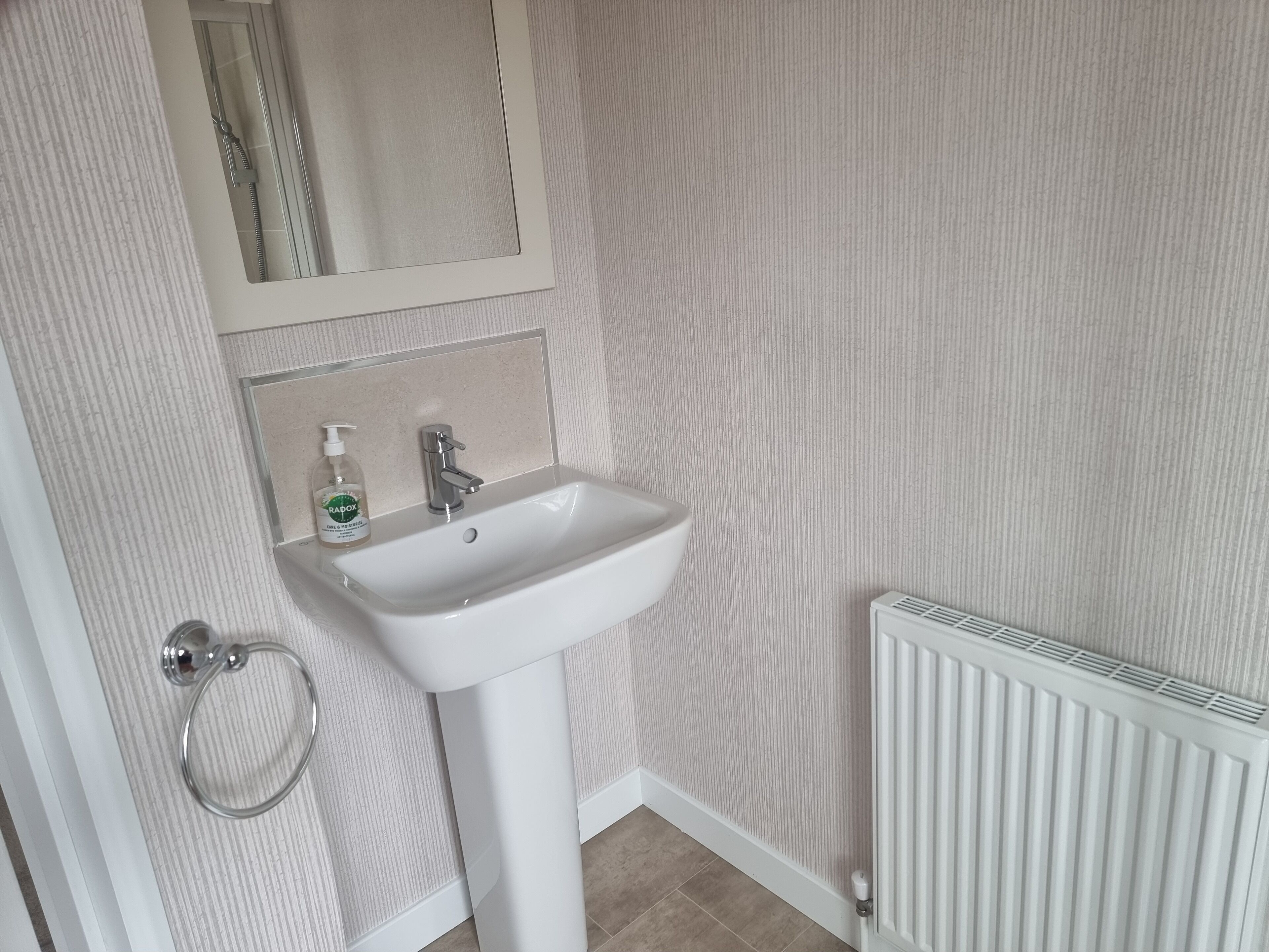 A bathroom with a white sink, a mirror, and a towel rack.