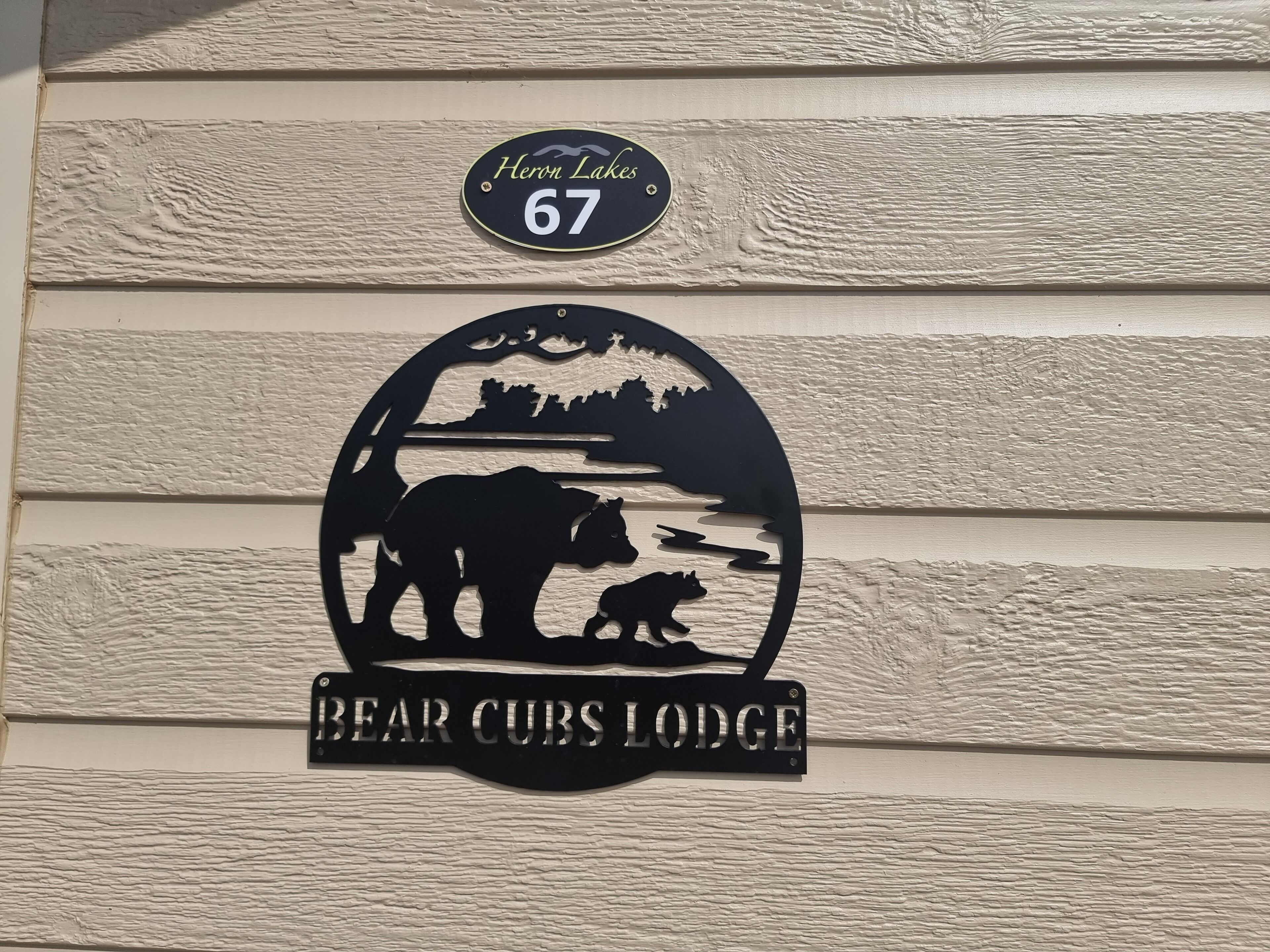 En husnummerplakett med en silhuett av en björn och texten ”Bear Cubs Lodge” under.