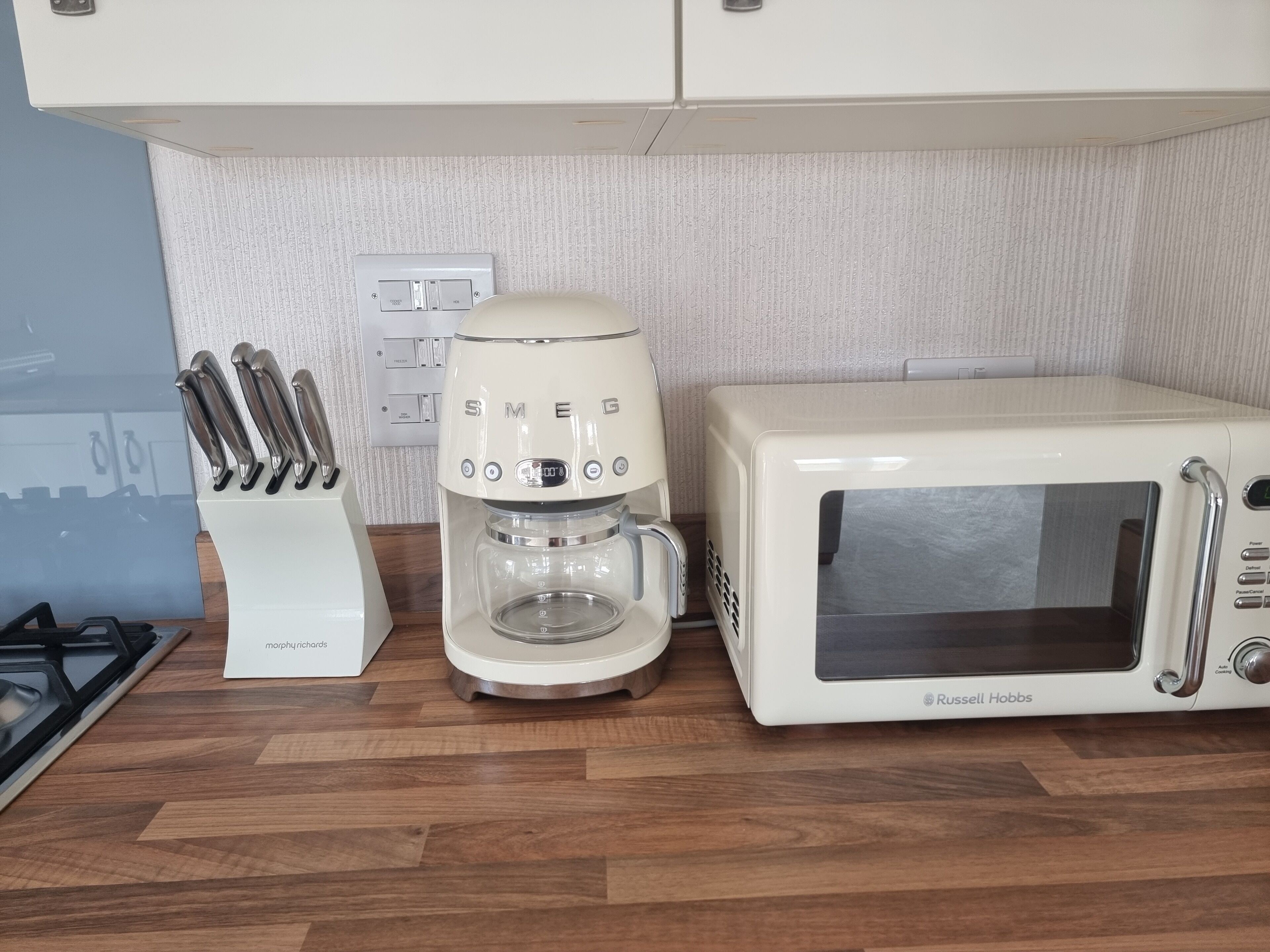 Una cocina con una cafetera blanca, un microondas blanco y un juego de cuchillos.