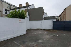 A narrow alleyway with a white wall, a grey door, and a black gate. - The Bells HOT TUB on Private Terrace Apartments (Blackpool)