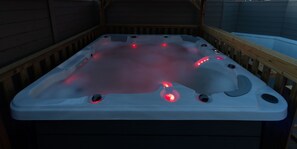 A hot tub with red lights, wooden deck, and a wooden wall in the background. - The Bells HOT TUB on Private Terrace Apartments (Blackpool)