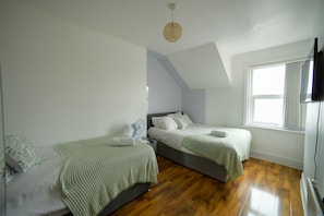 Cozy bedroom with two twin beds, a flat-screen TV, and a large window.
