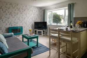 Cozy living space with a sofa, dining area, and television, offering a view of the outdoors.