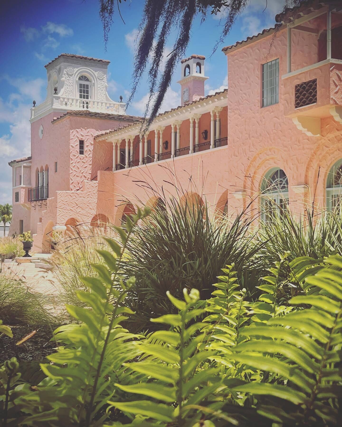 Un edificio con fachada rosa, detalles decorativos blancos y una torre.
