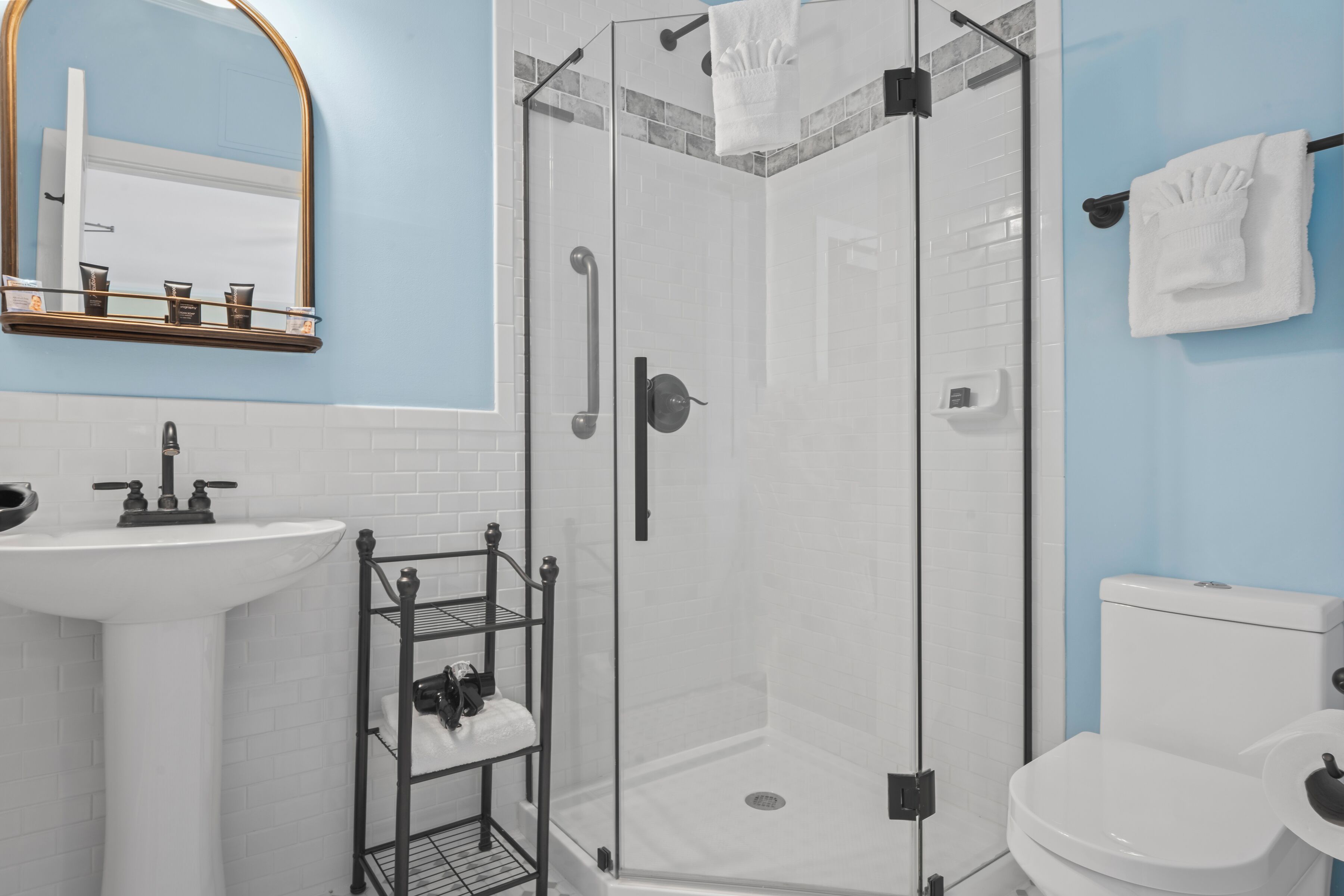 Une salle de bain avec un lavabo blanc, une douche à parois de verre, des toilettes et un porte-serviettes.