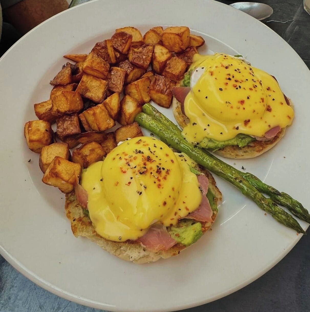 A plate with eggs benedict, roasted potatoes, and asparagus.