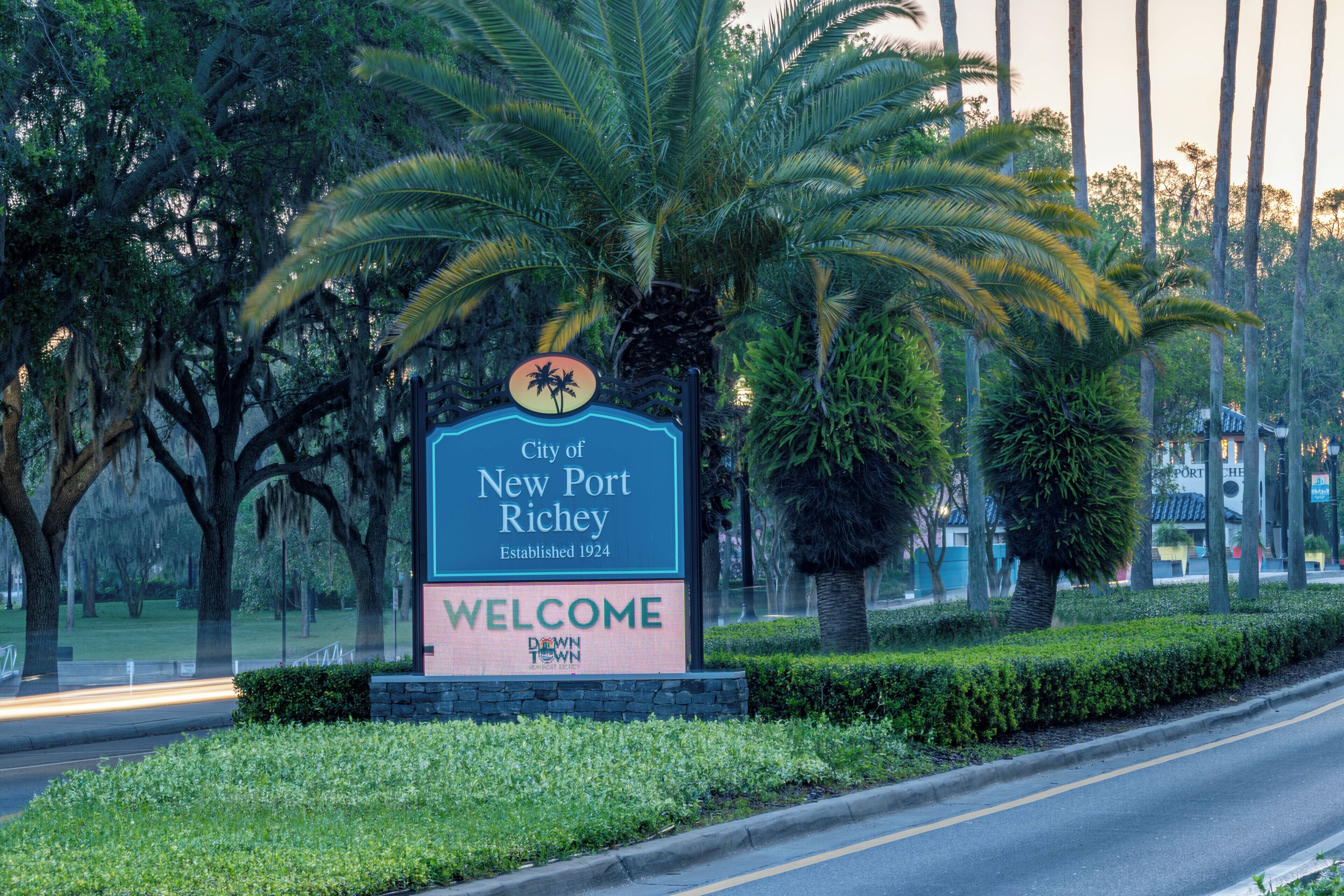 Welkomstbord voor de stad New Port Richey, met een palmboom en groen in de achtergrond.