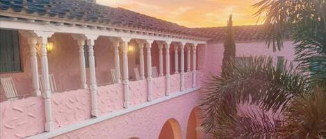 A pink building with a covered patio area featuring arches and columns.