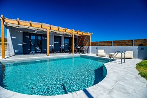 A modern outdoor pool area with a pergola, lounge chairs, and a clear blue pool. - Aurelia Villa (Zakynthos)