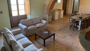 Un'ampia zona giorno con un arco in pietra, un divano, un tavolino da caffè e un tavolo da pranzo con sedie.
