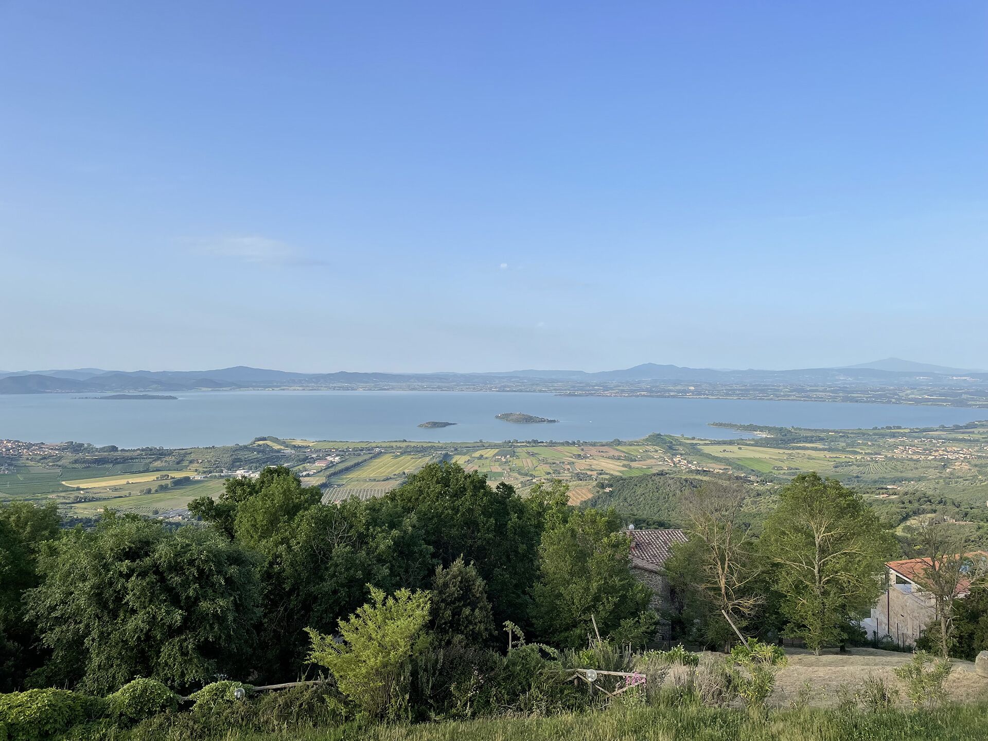 A coastal landscape with a view of the sea, hills, and scattered buildings.