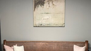 A wooden bench with two pillows against a grey wall, a painting above it, and a herringbone-patterned floor. - Family suite sleeps 11!  We are near Champaign-Urbana 4 bedrooms & 2.5 bathrooms (Saint Joseph)