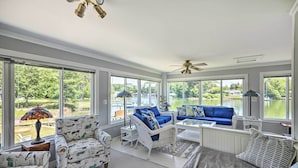 A sunroom with large windows, a ceiling fan, and a view of a lake. - Idyllic Waterfront Home w/ Game Room & Dock (Reedville)