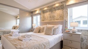 A modern hotel room with a large bed, a nightstand, a mirror, and a view of the outside. - Marshwiggle, Aldeburgh (Aldeburgh)