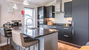 A modern kitchen with dark cabinets, a granite countertop, and pendant lighting. - Marshwiggle, Aldeburgh (Aldeburgh)