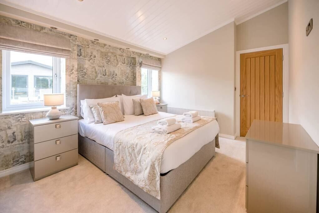 Une chambre à coucher avec un grand lit, une table de chevet, une commode et une fenêtre donnant sur un beau paysage.