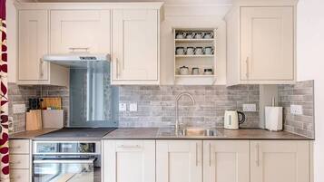 A modern kitchen with light-colored cabinets, a stainless steel sink, and a built-in oven.