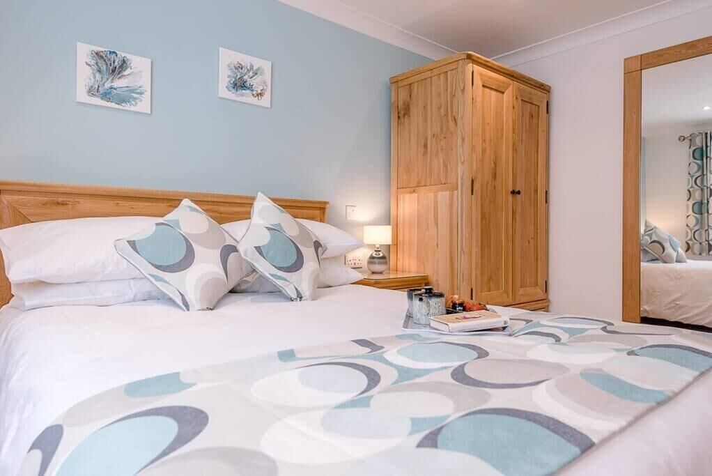 A bedroom with a bed, pillows, a nightstand, a wooden wardrobe, and two wall art pieces.