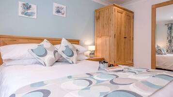 A bedroom with a bed, pillows, a nightstand, a wooden wardrobe, and two wall art pieces.