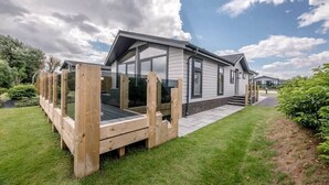 A modern house with a large deck, a covered porch, and a well-maintained lawn. - Briargate, Aldeburgh (Aldeburgh)