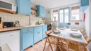 A kitchen with blue cabinets, a white refrigerator, and a dining table set for four.