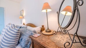 A bedroom with a wooden dresser, a mirror, two lamps, and a bed with striped pillows.
