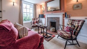A cozy living room with a fireplace, a sofa, a chair, and a television.